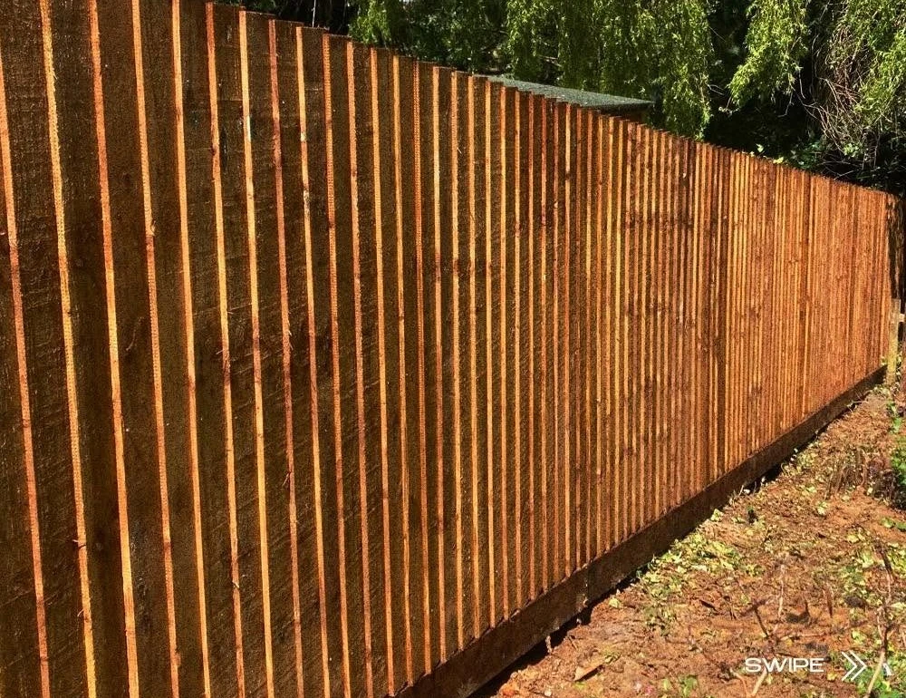 Timber fence beside mature trees by Boothville Services.