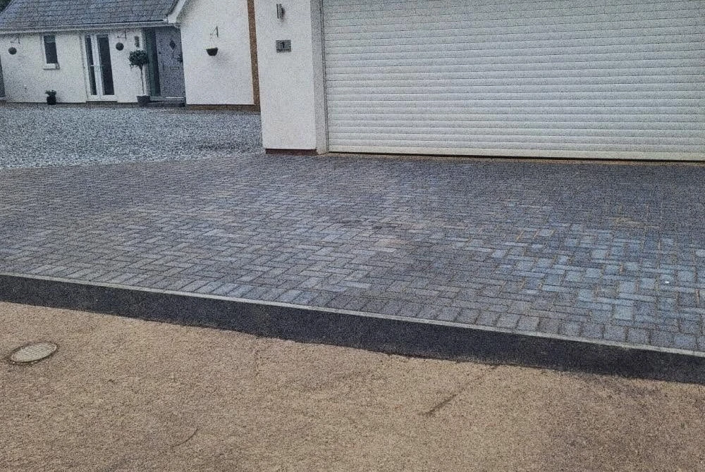 Finished grey block paving beside a garage by Boothville Services.