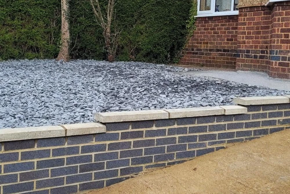 Rebuilt garden wall enclosing a gravel bed by Boothville Services.