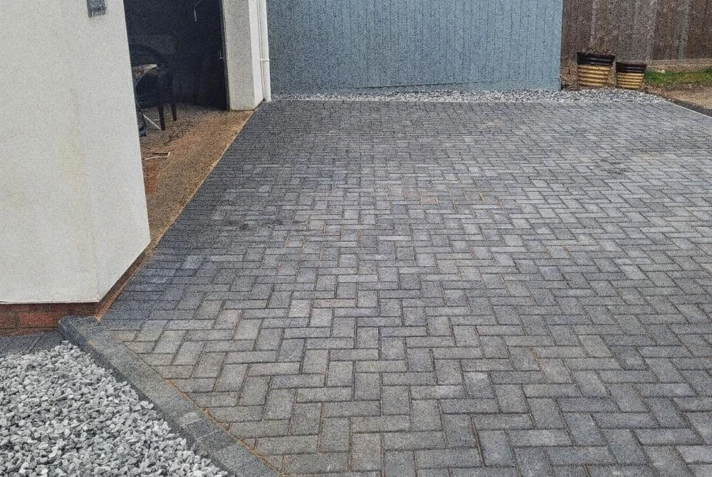 Block-paved driveway leading to a metal garage by Boothville Services.