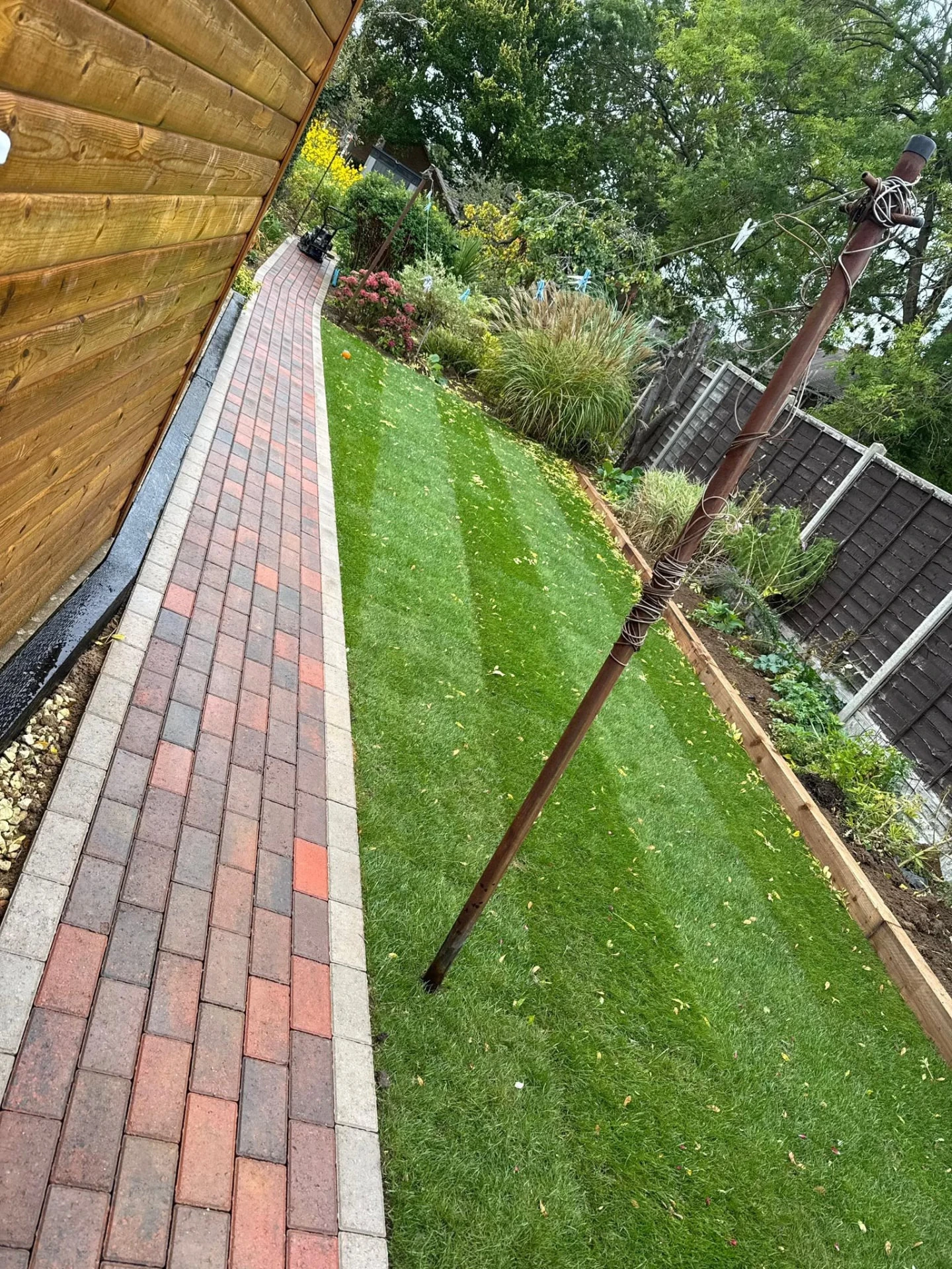 Curved block-paved garden path beside a lawn by Boothville Services.