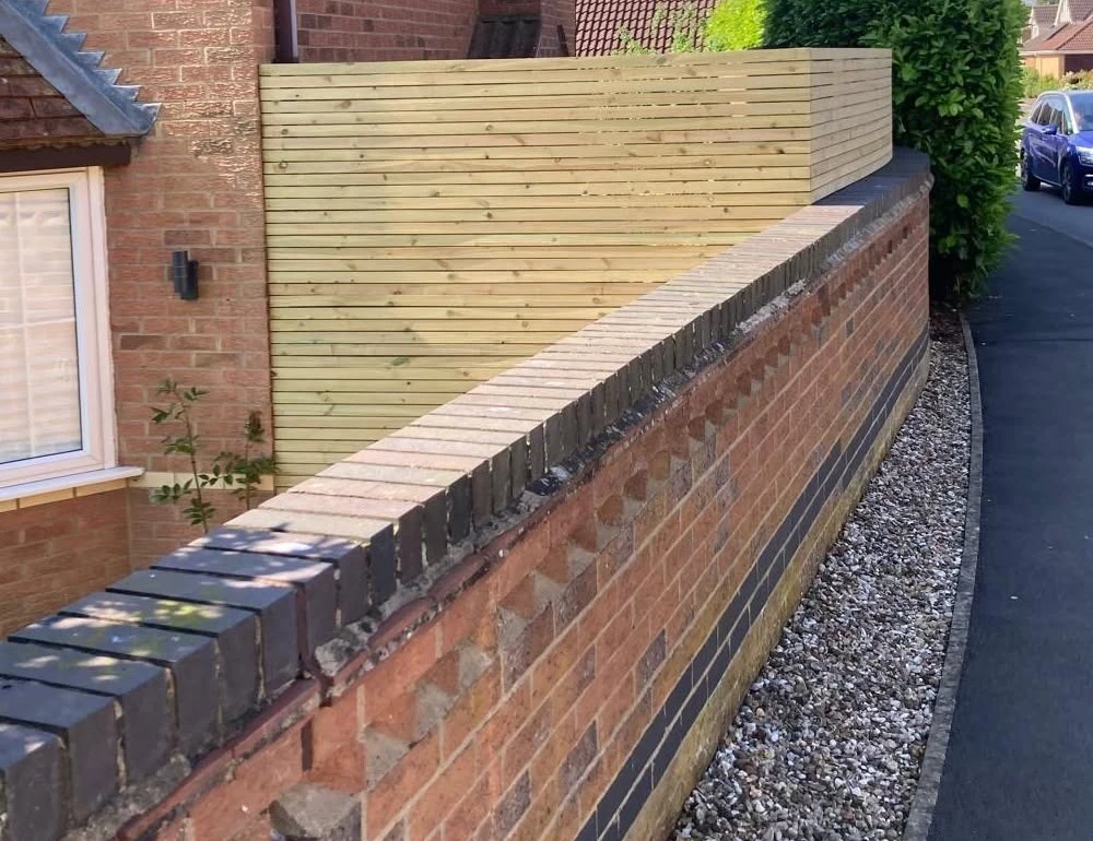 Horizontal timber slats following a curved brick wall by Boothville Services.