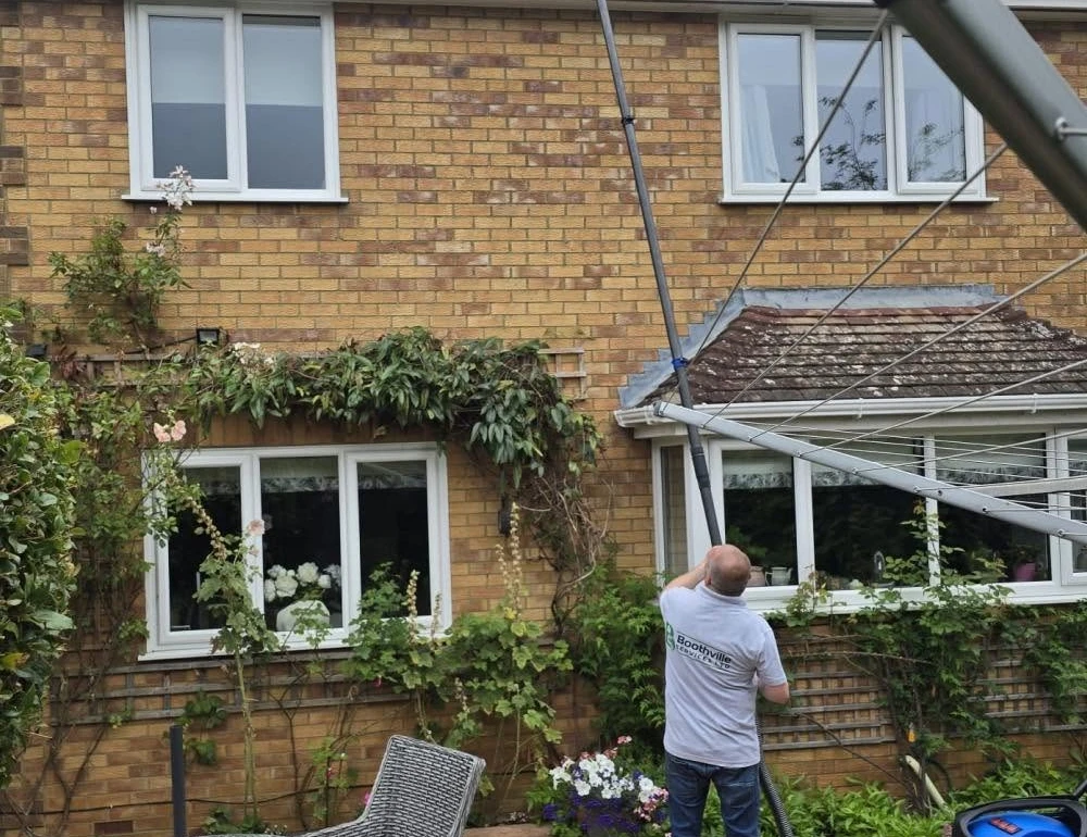 Worker cleaning roof-mounted solar panels by Boothville Services.