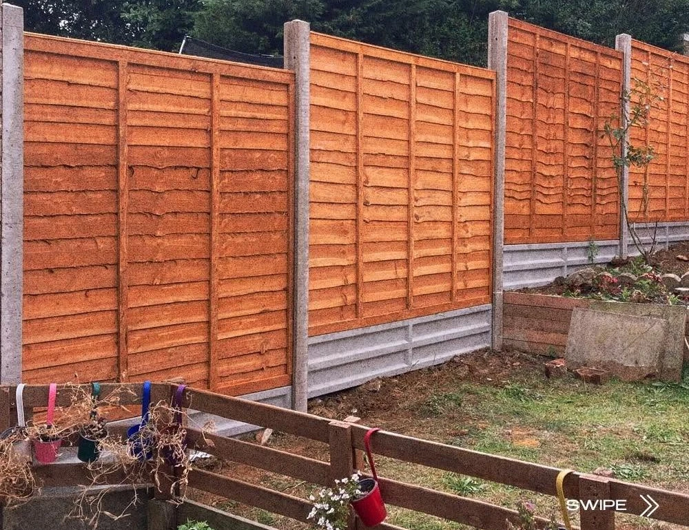 Long timber fence with concrete posts by Boothville Services.