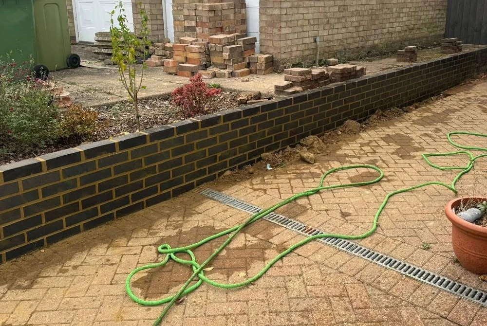 New brick retaining wall beside a paved driveway by Boothville Services.