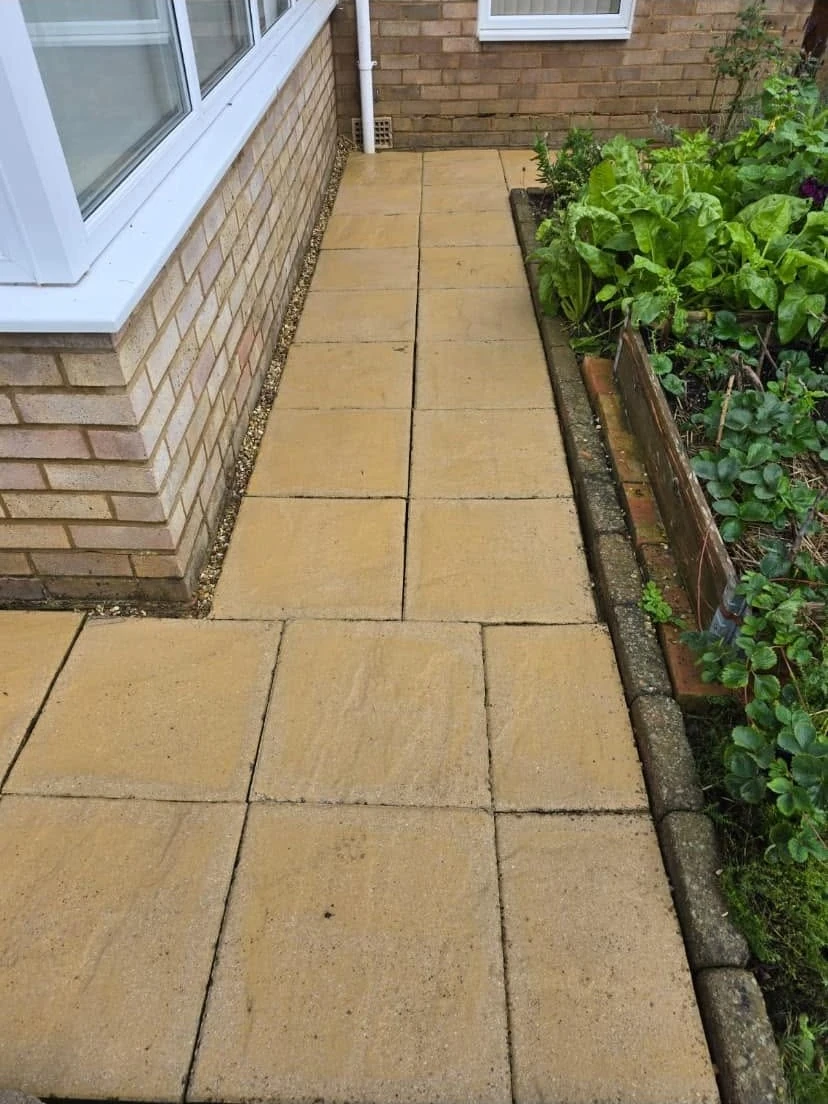 Cleaned pale paving slabs beside a planted border by Boothville Services.